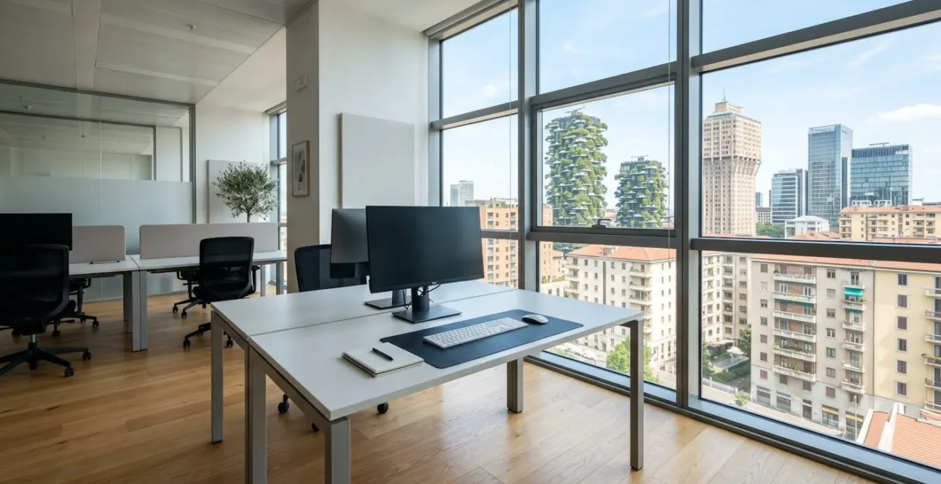 Interno di un ufficio moderno italiano vuoto con scrivania pulita, monitor spento e grande finestra che mostra architettura urbana italiana contemporanea, illuminato da luce naturale abbondante